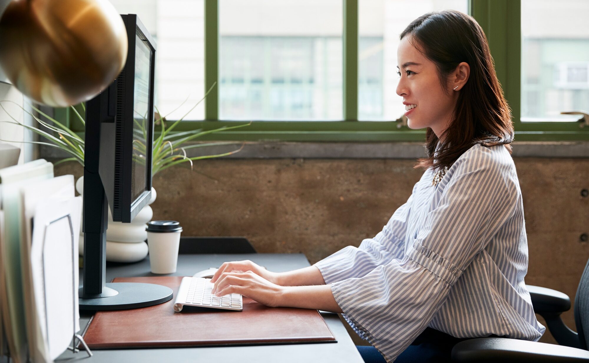 Chinese woman working at a computer in an office, side view